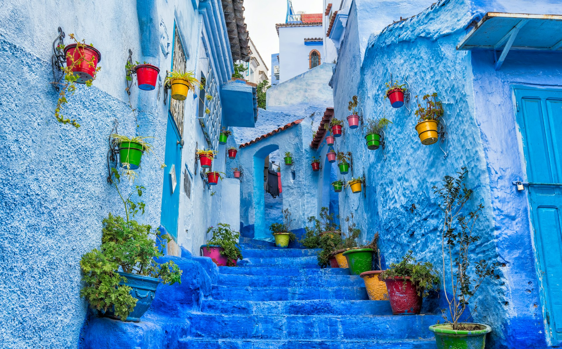 a narrow street with blue steps and potted plants